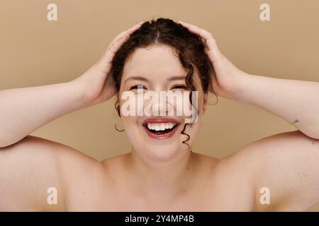 Una donna allegra e grande irradia fiducia e felicità toccando giocosamente i capelli. Foto Stock