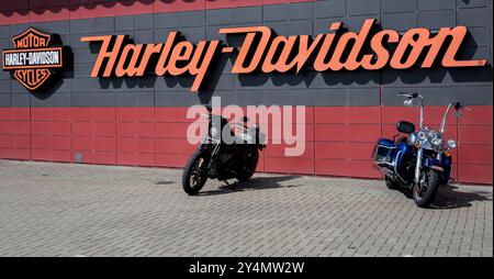 Minsk, Bielorussia, 19 settembre 2024 - due motociclette classiche in piedi vicino al cartello e al logo Harley-Davidson sul negozio della concessionaria Foto Stock