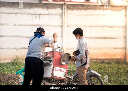 Persone che comprano spuntini da un venditore di cibo di strada. Gli spuntini conosciuti come 'Cilok o Bastus acronimo Baso Tusuk' in Indonesia, sono un piatto a base di tapioca Foto Stock