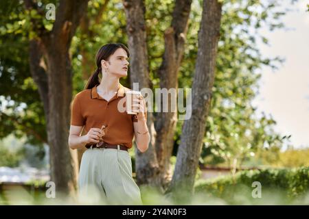 Una persona giovane si diverte a bere un caffè mentre si riflette in uno spazio verde all'aperto per uffici. Foto Stock