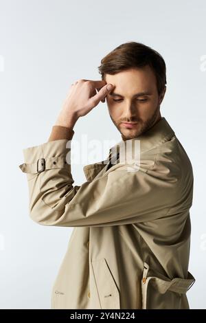 Un bell'individuo sfoggia una posa elegante, persa nel pensiero mentre è vestito con eleganza. Foto Stock
