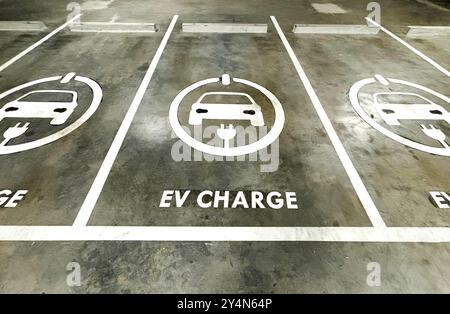 Spazio vuoto di parcheggi per la ricarica di veicoli elettrici in un edificio aziendale, segno di carica per veicoli elettrici sul terreno dei parcheggi. Foto Stock