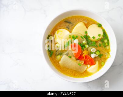 Primo piano zuppa Miso su un tavolo in marmo bianco con luce naturale, zuppa sana giapponese fatta in casa con spazio per la copia. Foto Stock