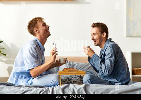 Una coppia felice condivide una mattinata accogliente in pigiama, sorseggiando un caffè e godendosi compagnia. Foto Stock