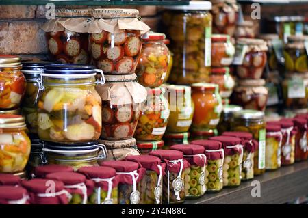 Varietà di vasetti di vetro pieni di verdure colorate conservate esposte su uno scaffale in un negozio di alimentari Foto Stock