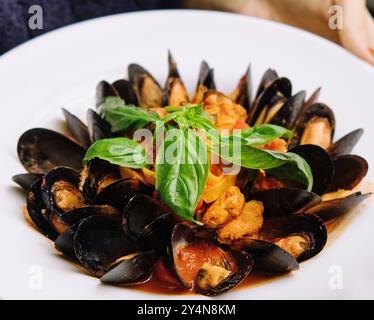 Deliziose cozze appena cotte al vapore in salsa di vino bianco in un piatto bianco Foto Stock