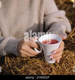 Una donna tiene una tazza di tè da vicino Foto Stock