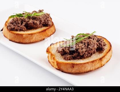 deliziosa bruschetta italiana con patè di tartufo su piatto bianco Foto Stock