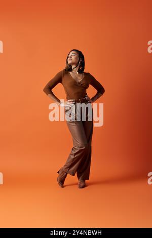 Una giovane donna sfoggia i suoi eleganti capelli intrecciati e l'elegante outfit in un vivace ambiente da studio. Foto Stock