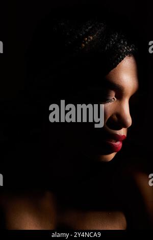 Una giovane donna afroamericana affascina lo studio con le sue audaci labbra rosse. Foto Stock