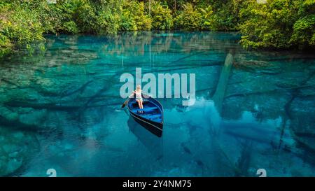 Donna in barca che galleggia in un lago tropicale trasparente con acqua dolce blu cristallina a Sulawesi, Indonesia. Vista aerea Foto Stock