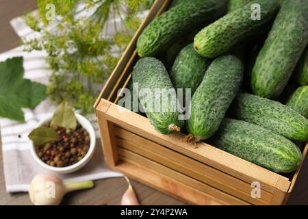 Cetrioli verdi freschi in cassa di legno sul tavolo, primo piano Foto Stock