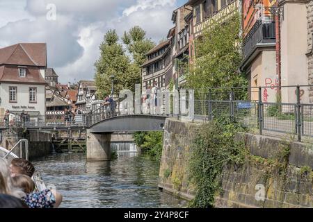 STRASBURGO, 2024 sett 04: Paesaggio urbano con battello turistico che si avvicina alla chiusa sulla riva del fiume malato a Petite France Borrough, girato alla luce brillante dell'estate Foto Stock