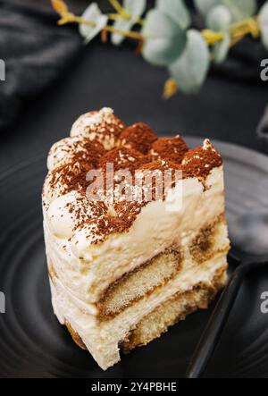 Tradizionale tiramisù italiano su piatto nero Foto Stock