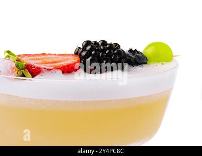 Primo piano cocktail giallo con schiuma bianca e frutti di bosco Foto Stock