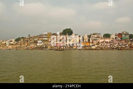 Piogge monsoniche, pellegrini e rituali di cremazione lungo il fiume Gange sono visti nella città Santa di Varanasi in India Foto Stock