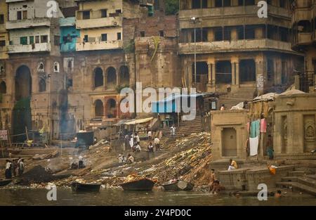 Piogge monsoniche, pellegrini e rituali di cremazione lungo il fiume Gange sono visti nella città Santa di Varanasi in India Foto Stock