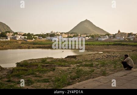 Piogge monsoniche, pellegrini e rituali di cremazione lungo il fiume Gange sono visti nella città Santa di Varanasi in India Foto Stock