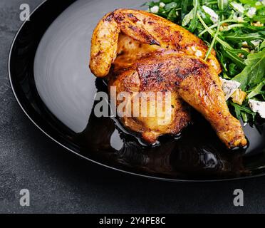 pollo fritto con insalata di rucola su piatto nero Foto Stock