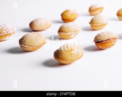 Biscotti a forma di noce con crema su bianco Foto Stock