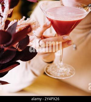 la giovane donna beve un cocktail rosso con fragole Foto Stock