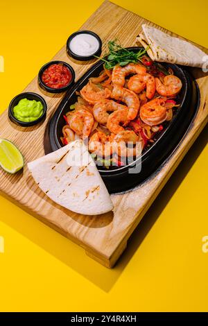 Gamberi grandi fritti con cipolle e peperoni in una padella Foto Stock