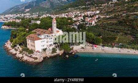 Annidato tra acque azzurre e vegetazione lussureggiante, il pittoresco villaggio sull'isola di Bol Brac delizia i visitatori con le sue spiagge tranquille e l'affascinante architettura, il tutto sotto il sole croato. Foto Stock