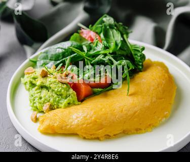 Omelette servita con purea di avocado e pomodori ciliegini Foto Stock