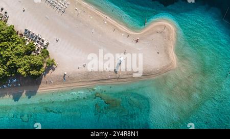 I visitatori passeggiano lungo le spiagge sabbiose dell'isola di Brac, circondati da acque cristalline. L'atmosfera vibrante invita al relax e all'avventura in una splendida giornata di sole. Zlatni Rat Beach Croazia Foto Stock