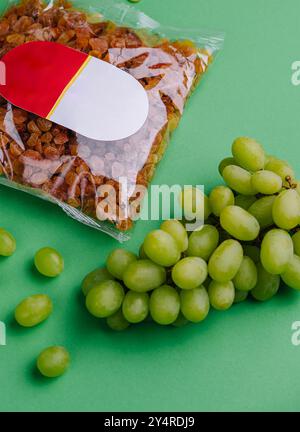 uva passa confezionata e uva su sfondo verde Foto Stock