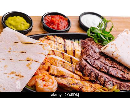 Fajitas di manzo e gamberi su un piatto di ghisa sfrigolante Foto Stock