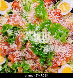 Insalata con salmone, lattuga, uova sode, pomodori ciliegini e parmigiano Foto Stock