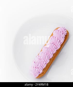 Dessert Eclair con panna montata rosa sul piatto Foto Stock