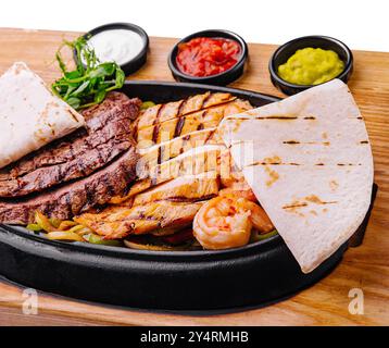 Fajitas di manzo e gamberi su un piatto di ghisa sfrigolante Foto Stock