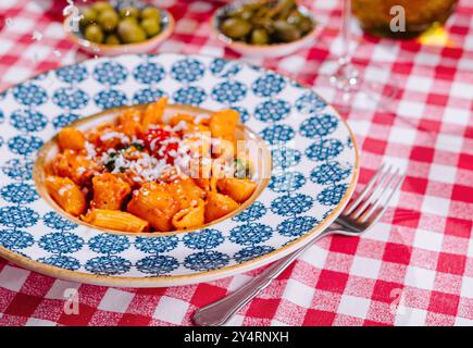 lo chef grattugia il formaggio al piatto con penne fresche Foto Stock