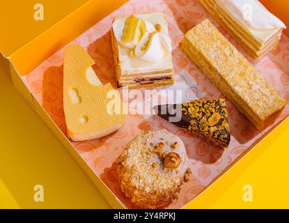 Regali di Natale con torte diverse su scatola gialla Foto Stock