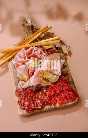 Selezione di salumi, carciofi e grissini serviti su un banco rustico Foto Stock