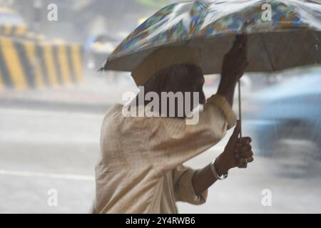 Mumbai, Maharashtra / India - 7 giugno 2008: Un vecchio che tiene stretto il suo ombrello tra le mani attraversando le strade durante la pioggia. Foto Stock