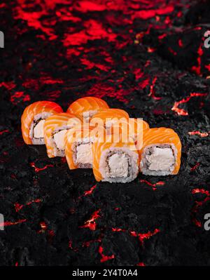 Squisiti sushi al salmone presentati ad arte su un fondo di carbone testurizzato Foto Stock