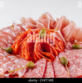 Stuzzicante selezione di salumi guarniti con capperi, presentati su un piatto elegante Foto Stock