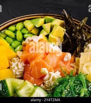 Vivace ciotola con salmone, mango, avocado e edamame su sfondo nero Foto Stock