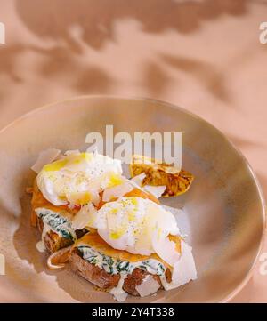 Elegante piatto per brunch con uova in camicia su un toast alle erbe aromatiche, guarnito con spezie Foto Stock