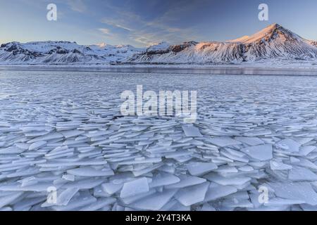 Piste di ghiaccio su un lago di fronte a montagne innevate, sole, luce notturna, neve, inverno, Snaefellsnes, Vesturland, Islanda, Europa Foto Stock