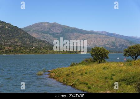 Paesaggio tranquillo con un lago circondato da prati verdi e montagne sotto un cielo azzurro, il bacino idrico di Embalse de Plasencia, Embalse de Jerte, Ri Foto Stock