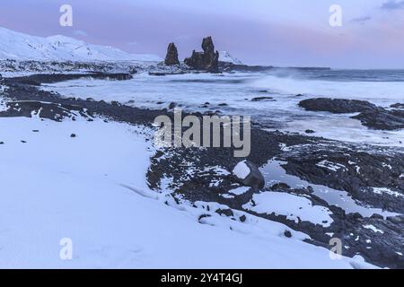 Rocce e surf sulla costa, luce notturna, sole, neve, inverno, Arnarstapi, Snaefellsnes, Vesturland, Islanda, Europa Foto Stock