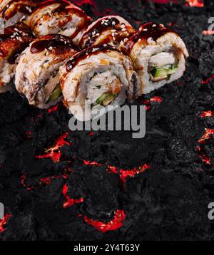 Presentazione creativa di sushi roll su una superficie ruvida simile alla lava, che esalta il fascino visivo della cucina giapponese Foto Stock