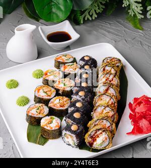 Selezione di sushi freschi serviti su un piatto bianco con salsa di soia, wasabi e zenzero sottaceto Foto Stock