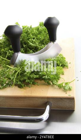 Prezzemolo tritato sul tagliere di legno Foto Stock