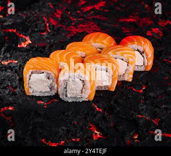 Squisiti sushi al salmone presentati ad arte su un fondo di carbone testurizzato Foto Stock