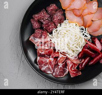 Vista dall'alto di una selezione di salumi con carni e formaggi su un piatto nero Foto Stock